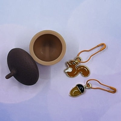 Mini silicone acorn-shaped jar with an enamel squirrel and nut-shaped knitting and crochet stitch markers
