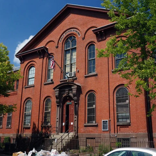Red brick building with large windows and a flag on a clear day